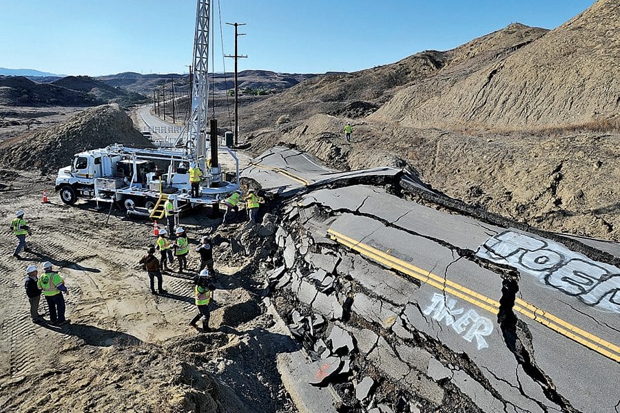 Los Angeles County Public Works workers drill a hole into the earth next to Vasquez Canyon Road as they prepare to lower engineering geologist Karin Burger into the hole to investigate why the road began to slide in late November. KATHARINE LOTZE/SIgnal. 12152015